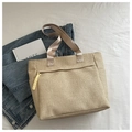 Detail of beige woven straw tote bag with brown handles and yellow rope tassel detail - Khaki