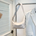 Borsa hobo bianca lucida con fibbie argentate e tracolla larga appesa a un gancio - Bianco