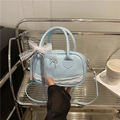 Borsa bowling azzurra con pizzo e fiocco argento tenuta in mano da un modello - Blu