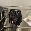 Chic black sequin bucket bag with silver chain strap shown in a modern urban setting - Black