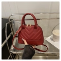 Macro detail van rode gewatteerde schelpvormige tas met gouden hardware en V-patroon - Rood
