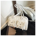Detail of white leather shoulder bag featuring bow ties, studs, and a mirror reflection - White