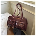 Detailed view of dark red shoulder bag with multiple front pockets and leather bows - Red