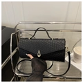 Schwarze Handtasche mit Krokodilprägung, Goldverschluss und Riemen im Regal - Schwarz