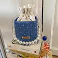 Detailed view of denim bucket bag with pearl handle and cream drawstring closure - Blue