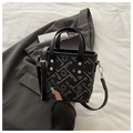 Dettaglio di motivi geometrici ricamati e trame floreali su una borsa tote nera - Nero