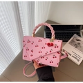 Detailansicht der rosa Kirsch-Handtasche mit gedrehten Griffen und Anhänger - Rosa