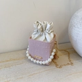 Detailed macro of pink textured mini bucket bag with pearl handle and golden chain - Pink