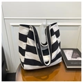 Detalle del bolso tote de lona con rayas negras y blancas sobre mesa redonda - Negro