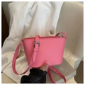 Detailed shot of pink bucket bag with silver metal buckles and logo on corduroy background - Pink