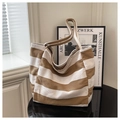Detalle del bolso tote de lona a rayas marrones y crema sobre escritorio moderno - Caqui