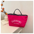 Dettaglio della borsa tote rosso rosa idrorepellente con manici intrecciati e tasca laterale - Rosso
