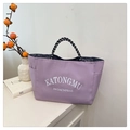 Detailed view of a purple tote bag featuring woven stripe handles and letter print - Pink