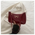 Detail of burgundy patent leather shoulder bag featuring a gold metal bow and chic texture - Red