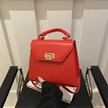 Classic red leather top-handle bag with gold square buckle shown on a black chair - Red
