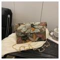 Brown woven bag with colorful floral embroidery and gold chain strap in a lifestyle setting - Brown