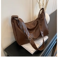 Detailed view of dark brown PU leather shoulder bag with pleated texture on black desk - Brown