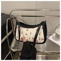 Detailansicht der Schultertasche mit Kirschmuster und schwarzem Gurt im Regal - Schwarz