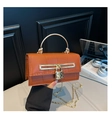 Detail of amber orange embossed leather bag with gold handle and heart lock charm - Brown