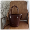 Detalle de bolso bucket de cuero burdeos con letras Fashion plateadas en silla madera - Marrón Oscuro
