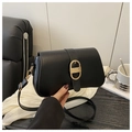 Detail of black leather shoulder bag featuring a large gold oval buckle with woven texture - Black