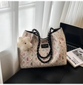 Detalle del bolso tote crema con estampado de oso, textura ondulada y colgante de estrella - Negro Con Colgante