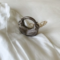 Detail view of semi-circular metallic handbag with twisted handle and gold chain strap - Black
