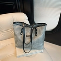 Grand sac cabas gris texturé avec rivets et poignées noires posé sur un canapé - Gris clair