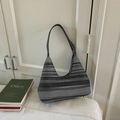 Knitted hobo shoulder bag with black and grey horizontal stripes on a white sofa - Black