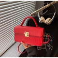 Détail d'un sac rouge motif crocodile avec fermoir doré dans un décor urbain chic - Bordeaux