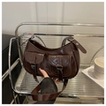 Nahaufnahme der braunen PU-Satteltasche mit Doppeltaschen und Silberschnallen auf Glasregal - Kaffeebraun