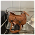 Close-up of brown leather handbag with silver buckles on a decorative silver cart - Brown