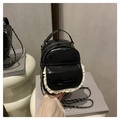 Mini mochila negra brillante con encaje blanco y lazo decorativo en un moderno estudio - Negro
