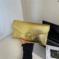 Golden envelope clutch bag with metal texture and H-shaped buckle shown in hand - Gold
