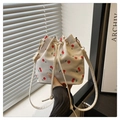 Macro shot of white drawstring bucket bag with cherry print and golden metal clasp - Cherry