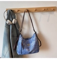 Detalle del bolso hobo de mezclilla azul con correa de cuero y logo en gancho de madera - Azul