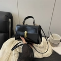 Glossy black patent leather mini handbag with gold buckle on white silk cloth - Black