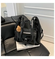 Detail of glossy black tote bag with white contrast stitching and plush bear charm - Black With Pendant