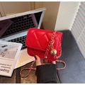 Détail d'un petit sac bandoulière rouge matelassé avec chaîne dorée et pendentif - Rouge