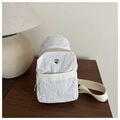 Dettaglio del marsupio bianco in nylon stropicciato con logo metallico sul tavolo - Bianco