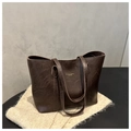 Détail d'un sac cabas en cuir marron foncé avec lettrage doré sur un tapis moelleux blanc - Brun Foncé