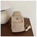 Dettaglio borsa pettorale in nylon kaki con trama impermeabile su legno scuro - Cachi