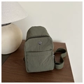Nahaufnahme der armee-grünen Nylon-Brusttasche mit Metall-Logo auf Holztisch - Grün