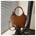 Détail d'un sac seau marron avec poignées tressées et logo DX embossé en doré - Marron