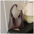 Primer plano de bolso tote de cuero trenzado marrón oscuro con correa ancha en un ambiente elegante - café