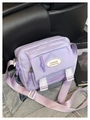 Details einer lavendelfarbenen Nylon-Umhängetasche mit weißen Kunststoffschnallen - Lila