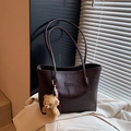 Brown leather tote bag with long straps and a plush bear pendant on a beige blazer - Coffee with Pendant