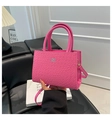 Pink croc-embossed handbag with gold hardware and detachable strap held by hand - Pink