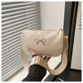 Close-up of cream square bag with gold bow detail and wide adjustable canvas strap - Off White