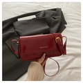Detalle del bolso de charol rojo oscuro con hebilla dorada y correa ajustable fina - Rojo